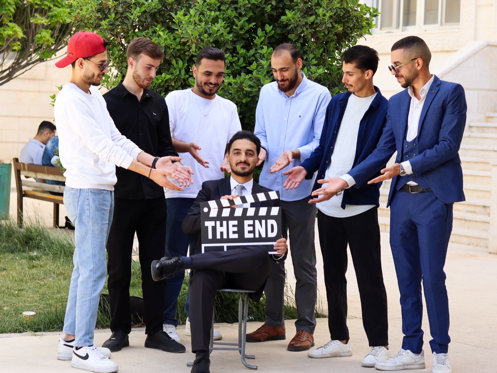 Graduation portrait in blue suit against hedges